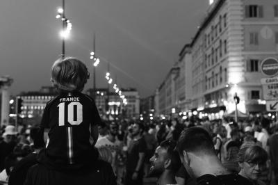 Black and white image of behind a crowd of sports fans lining the streets in France.