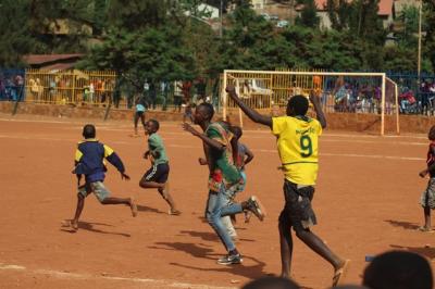 Boys playing football on sand pitch. 