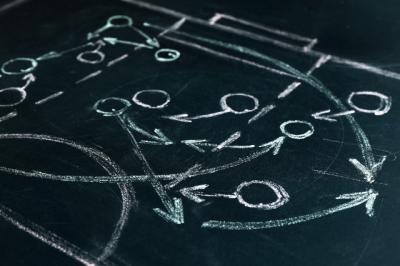 Close up image of white chalk drawing of a game plan on a chalk board. 