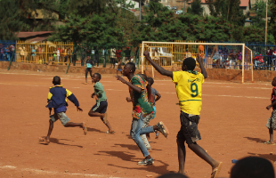 Boys playing football on sand pitch