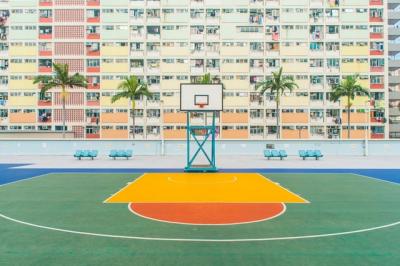 Empty basketball court in front of block of apartments.