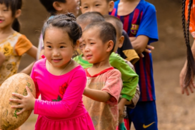 Young children holding rugby ball. 