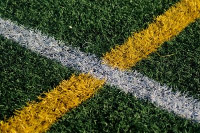 Close up image of painted lines on grass sports pitch.