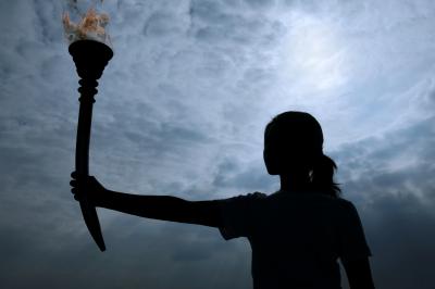 Silhouette of a female holding the olympic torch.
