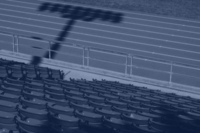 The back of empty sports stadium chairs facing the running track. 