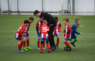 Young boys playing football with their coach 